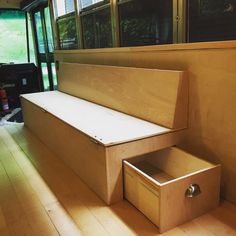 a wooden bench sitting on top of a hard wood floor next to a window filled with lots of windows