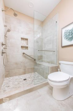 a white toilet sitting next to a shower in a bathroom under a framed picture on the wall