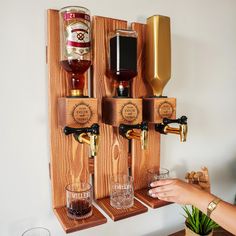 a person is holding a glass in front of a wall mounted beer dispenser