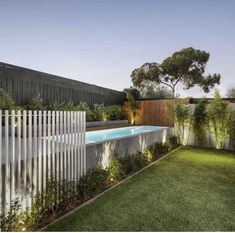 an outdoor swimming pool surrounded by greenery and fenced in area next to the house