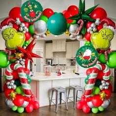 an arch made out of balloons and christmas decorations in a kitchen with bar stools