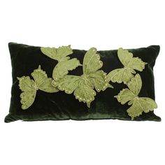 a green velvet pillow with leaf appliques on it