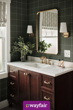 a bathroom with green walls and white counter tops, gold accents on the mirror above the sink