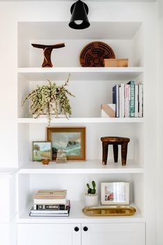 a white bookcase with books and pictures on it, along with other decor items