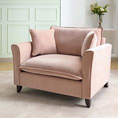 a pink chair sitting on top of a carpeted floor next to a vase with flowers