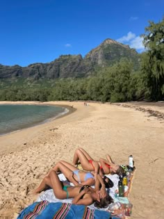 three women laying on the beach in their bathing suits and bikinis, drinking beer