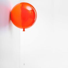 an orange balloon hanging from a white wall