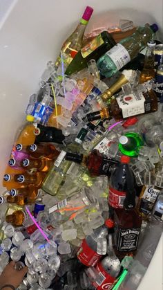 a bath tub filled with lots of different types of bottles and liquors in it