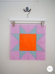 an orange and blue square is hanging on the wall next to a white coat rack