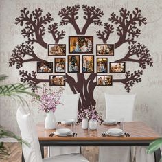 a dining room table with chairs and pictures on the wall above it, along with vases filled with flowers