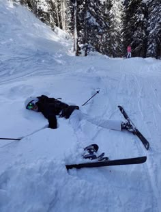 a person laying in the snow with skis and poles on their feet next to them