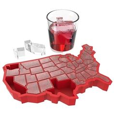 a red ice tray with a glass filled with water and an ice block shaped like the united states