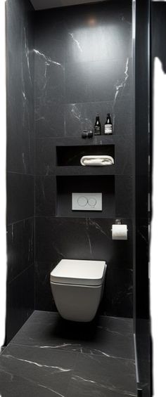 a black and white bathroom with toilet, sink and shelves on the wall in it