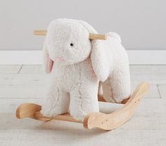 a white stuffed elephant sitting on top of a wooden rocking toy