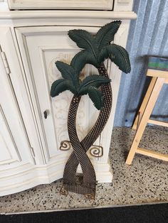 a fake palm tree sitting on top of a counter next to a chair and door