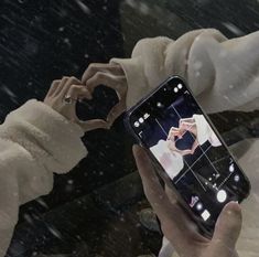 a person taking a photo with their cell phone in the snow while it's raining