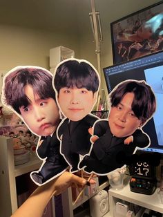 three stickers depicting the faces of two young men, one with black hair and one with brown eyes