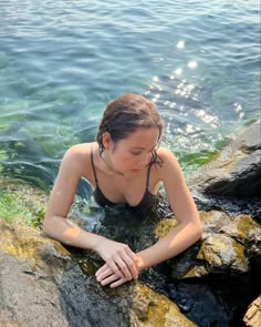 a woman sitting on rocks in the water