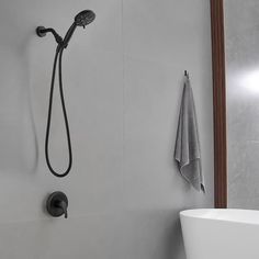 a bathroom with a tub, shower head and towel hanging on the wall next to it