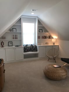 an attic bedroom with built - in bookshelves, shelves and a round ottoman