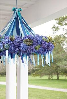 a blue and white flower arrangement hanging from the ceiling in front of a porch with grass