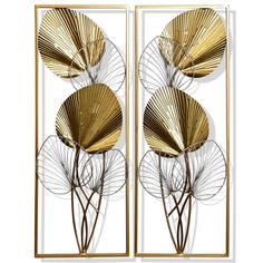 two golden metal wall art pieces with leaves on the sides and one has a mirror behind it