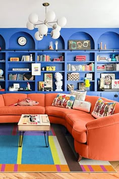 a living room with red couches and bookshelves on the wall behind them