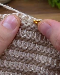 someone is crocheting the stitchs together with their fingers