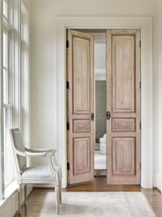 an open door leading to a bedroom with white walls and wood floors, along with a chair