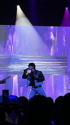 two men on stage singing into microphones in front of an audience at a concert