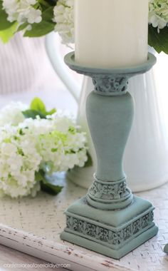 a white candle sitting on top of a table next to flowers