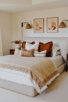 a large bed sitting in a bedroom next to two pictures on the wall above it