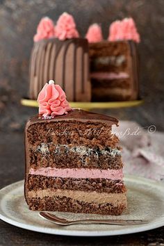 a slice of chocolate cake with pink frosting on a plate next to the rest of the cake