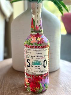 a bottle of alcohol sitting on top of a table next to a vase with flowers