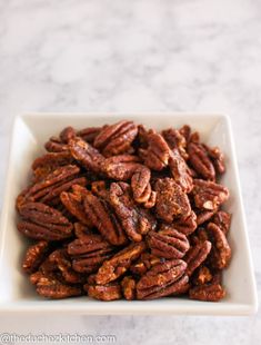 a white bowl filled with pecans on top of a table