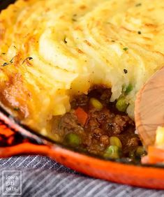 a close up of a casserole in a pan with a wooden spatula