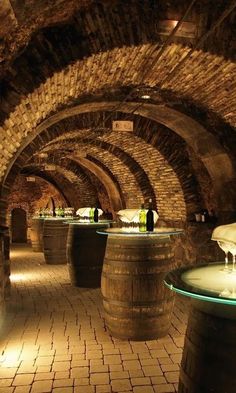 an underground wine cellar with several barrels lined up on the floor and tables in between them