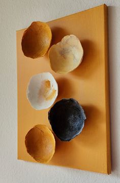 three different types of doughnuts on a yellow board next to a white wall