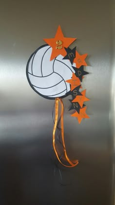 a metal refrigerator with orange and black stars on the bottom, and a volleyball ball hanging from it's side