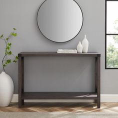 a modern console table with a round mirror on the wall above it and a vase next to it