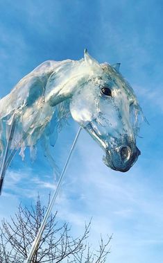 an ice sculpture of a horse is shown in the blue sky with trees and branches