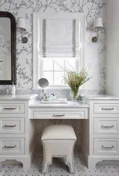 a white bathroom with two sinks and a large mirror above the sink is decorated in floral wallpaper