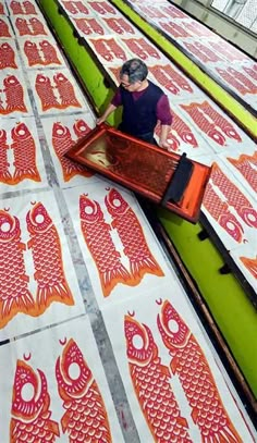 a man standing on top of a floor covered in red and white fish designs next to a green wall