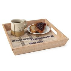 a wooden tray with a coffee cup and some food on it next to a piece of bread