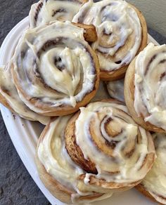 several cinnamon rolls with icing on a white plate