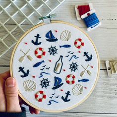 someone is holding up a embroidery hoop with various items on it and some thread spools