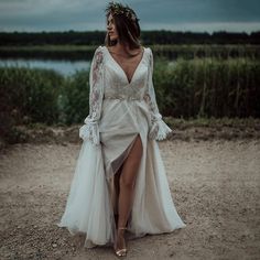 a woman in a white dress walking down a dirt road with her legs crossed and wearing a flower crown