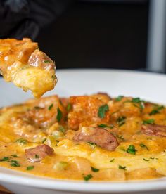 a spoonful of food is being held up in the air over a white bowl