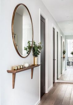 an iphone photo of a hallway with white walls and wood flooring on the phone