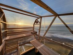 a wooden bench sitting on top of a balcony next to the ocean at sunset or sunrise